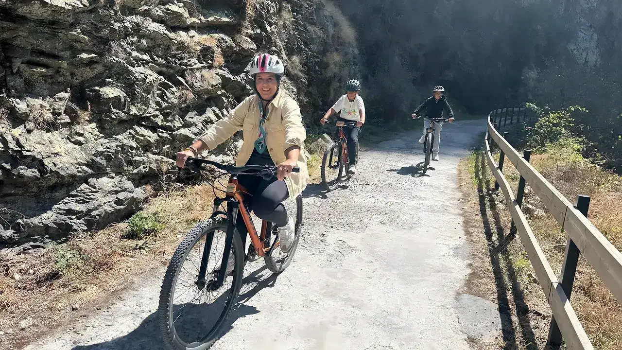 Grupo de ciclistas con casco pedaleando juntos por la Senda del Oso