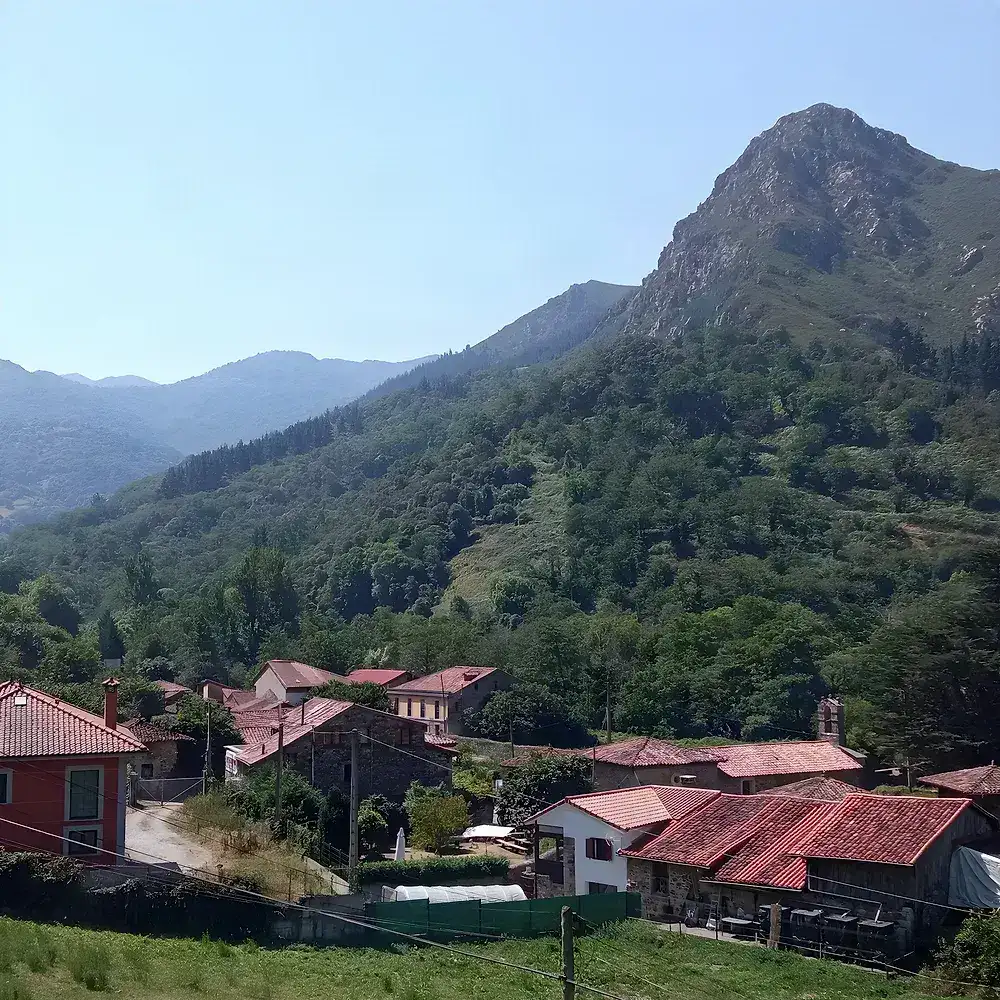 Casas de piedra y tejados rojos de Proaza bajo la montaña